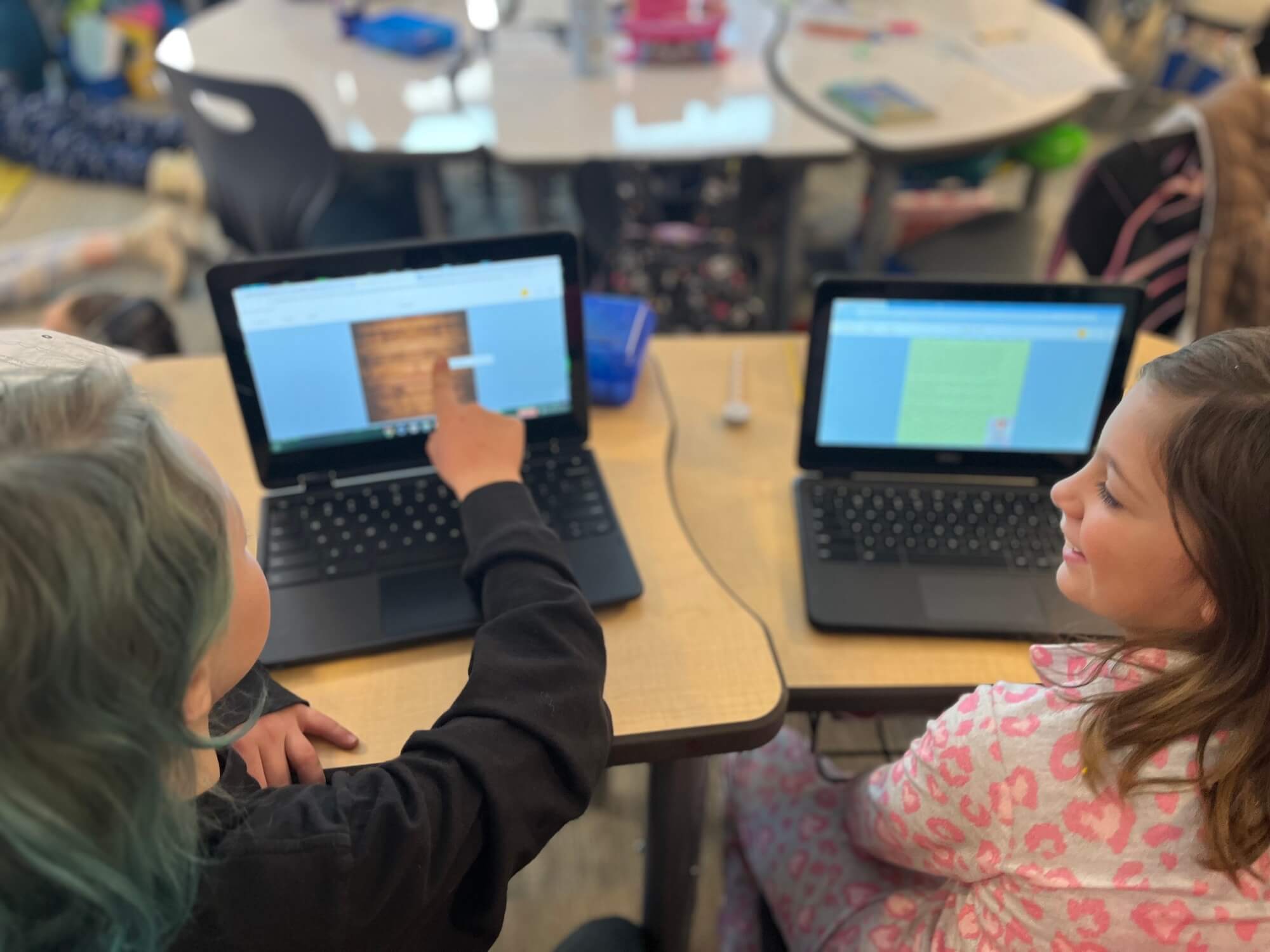 Two students using laptops to collaborate on digital storytelling projects in the classroom, engaging with educational technology tools like Book Creator to enhance their learning experience.